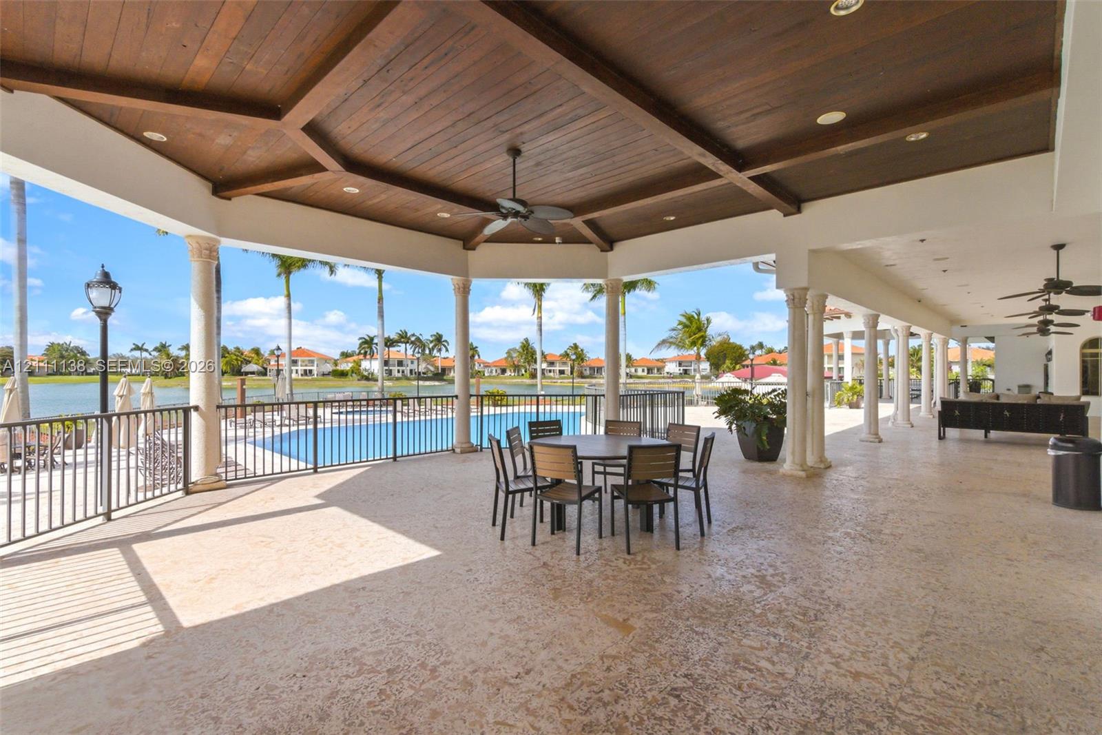 Covered lanai featuring a vaulted wood-plank ceiling, structural columns, recessed lighting, ceiling fans, and stone-finish flooring