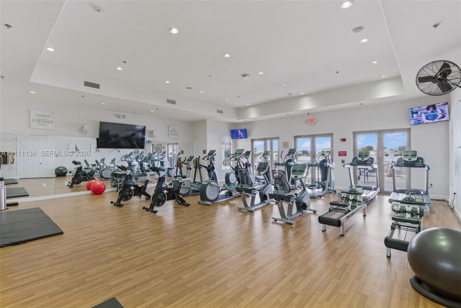 Fitness center featuring wood-finish flooring, recessed lighting, wall-to-wall mirrors, and double glass-paneled doors