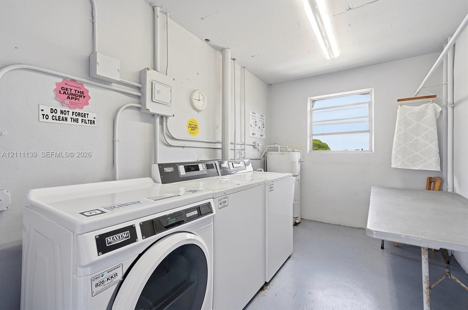 Utility room featuring painted concrete flooring, a horizontal louvered window, and overhead fluorescent lighting