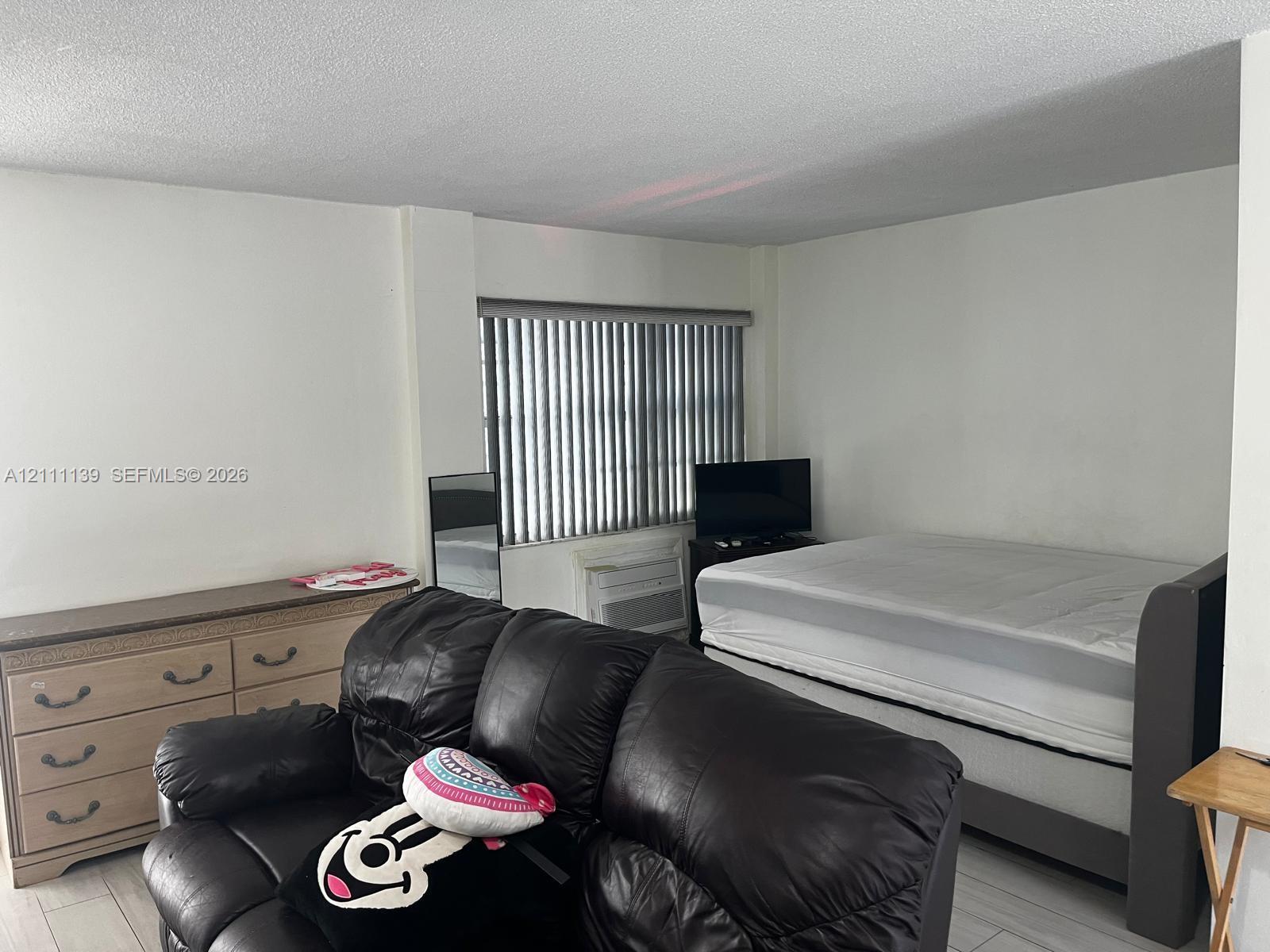 Interior space featuring neutral wall tones, light-toned flooring, and window treatments with vertical blinds Interior space featuring neutral wall tones, light-toned flooring, and window treatments with vertical blinds