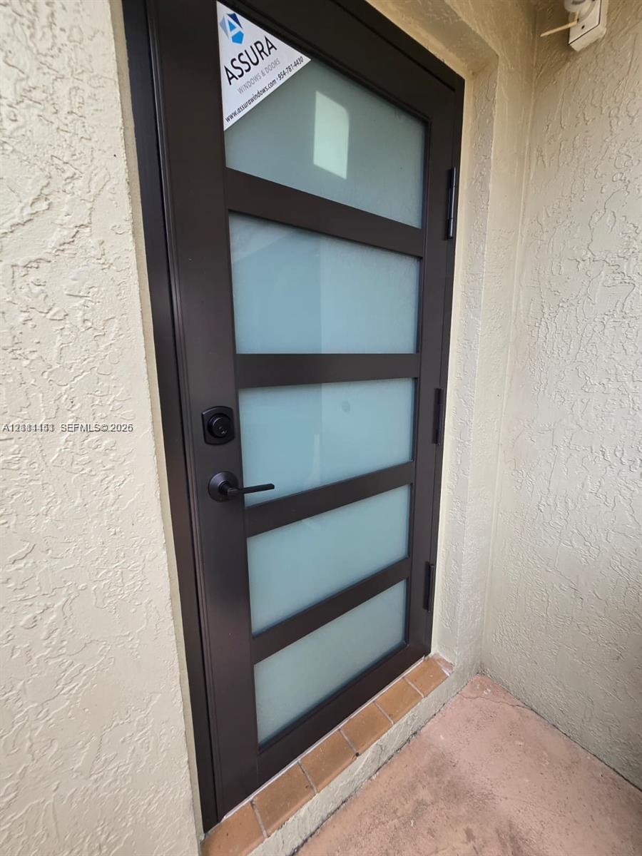 Modern exterior door featuring a dark metal frame, five horizontal frosted glass panels, and matte black lever hardware Modern exterior door featuring a dark metal frame, five horizontal frosted glass panels, and matte black lever hardware