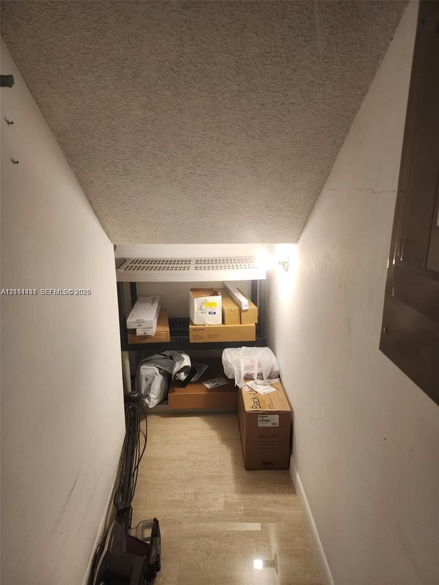 Enclosed storage space featuring stone-finish tile flooring and a slanted ceiling