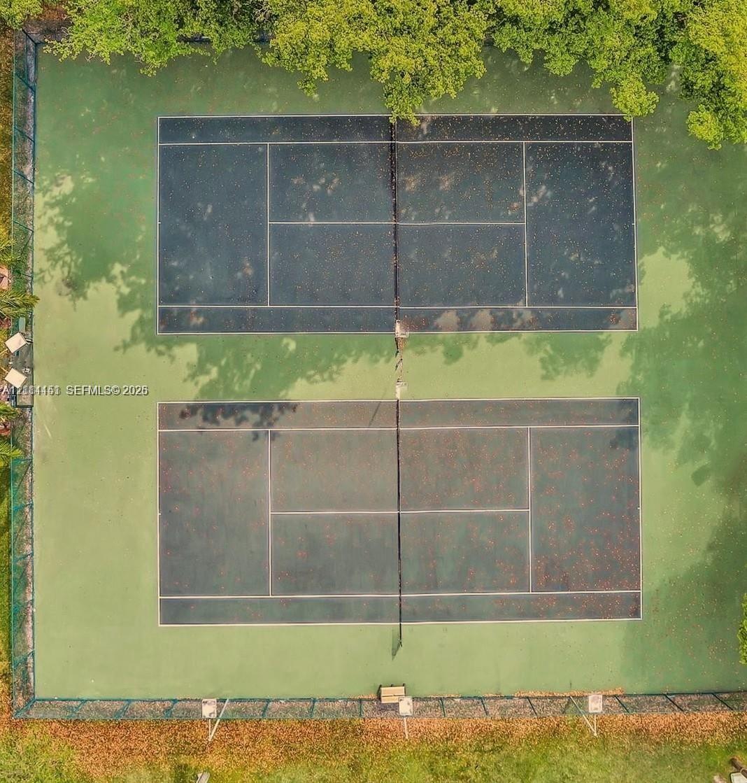 Two tennis courts featuring a multi-tone surface finish and perimeter chain-link fencing