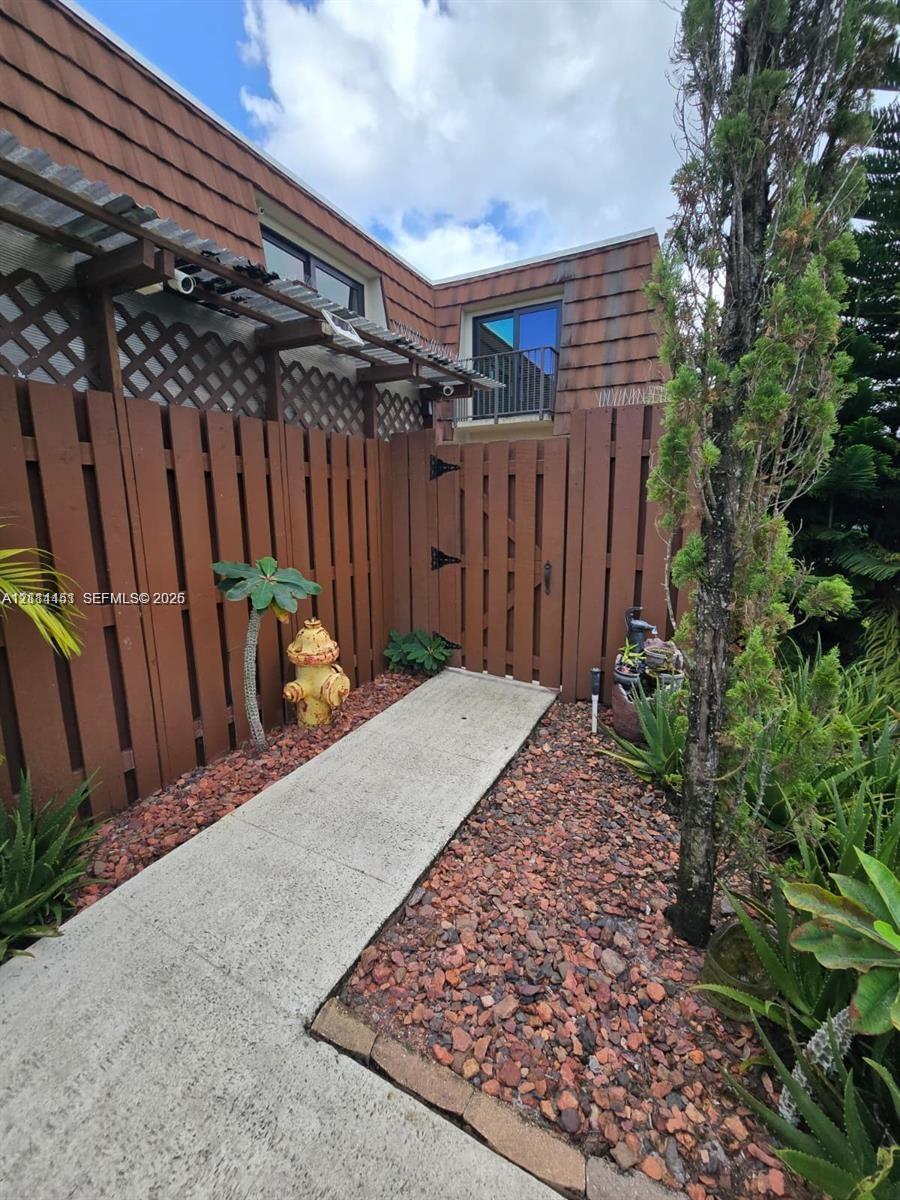 Concrete walkway leading to a private entrance, enclosed by a wood-slat privacy fence with integrated lattice detailing Concrete walkway leading to a private entrance, enclosed by a wood-slat privacy fence with integrated lattice detailing