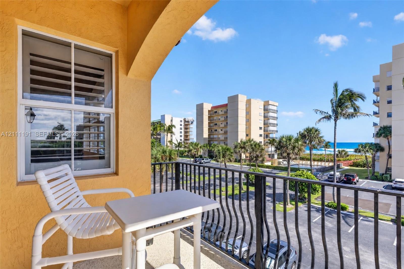 Covered balcony featuring a textured stucco finish, metal railings, and dual-pane window with integrated shutters