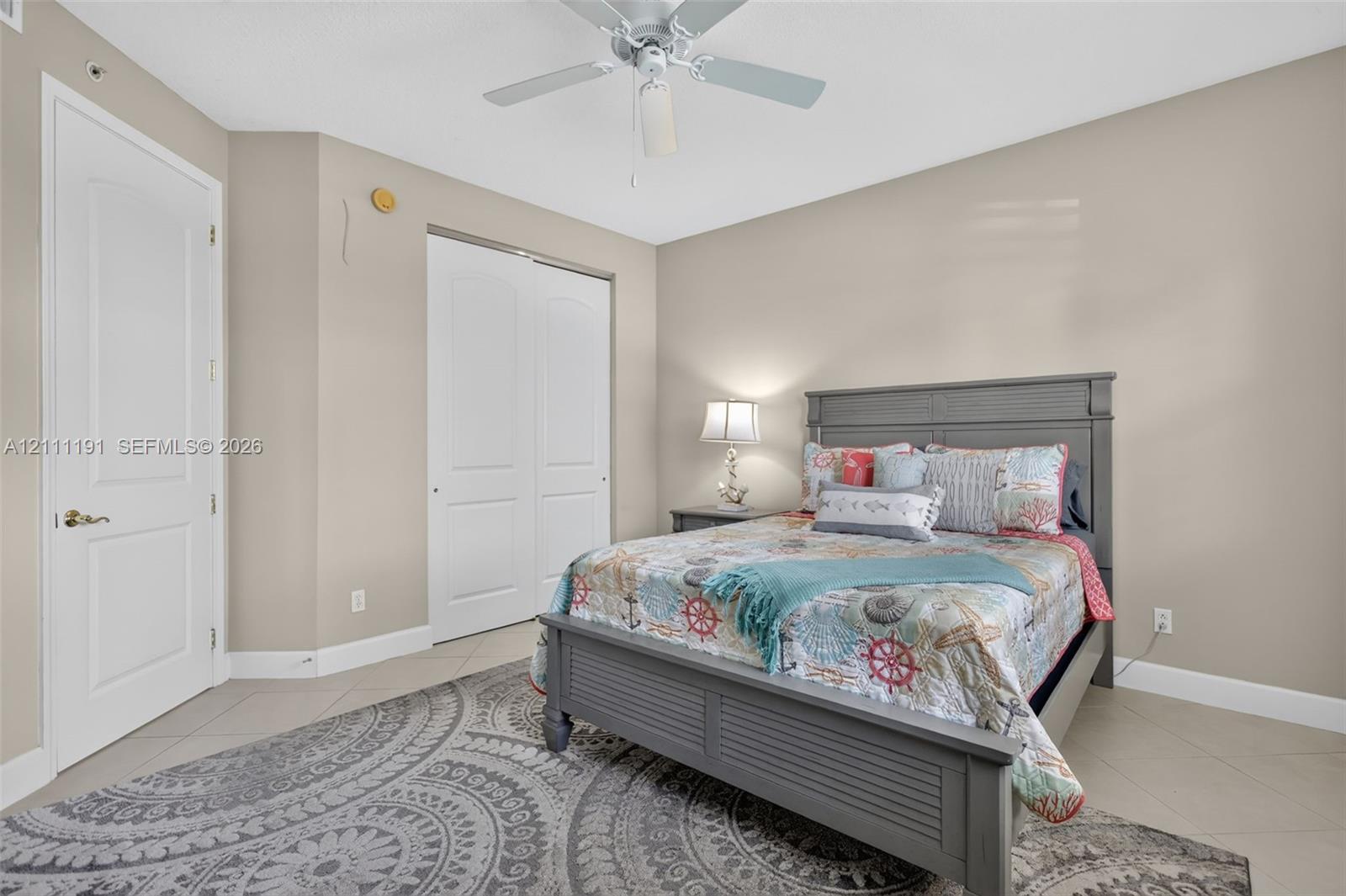 3rd Bedroom on 1st floor. Neutral-toned interior space featuring tile flooring, a ceiling fan with light fixture, and double-panel closet doors