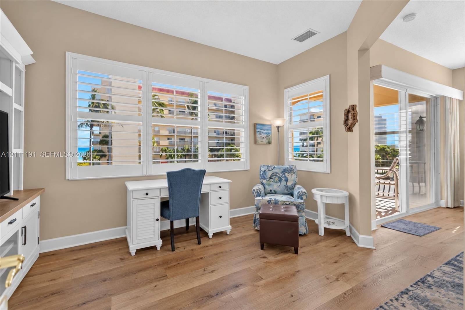 Sitting area off of PRIMARY BEDROOM. Wood-finish flooring, plantation shutters, entertainment center, and sliding glass doors