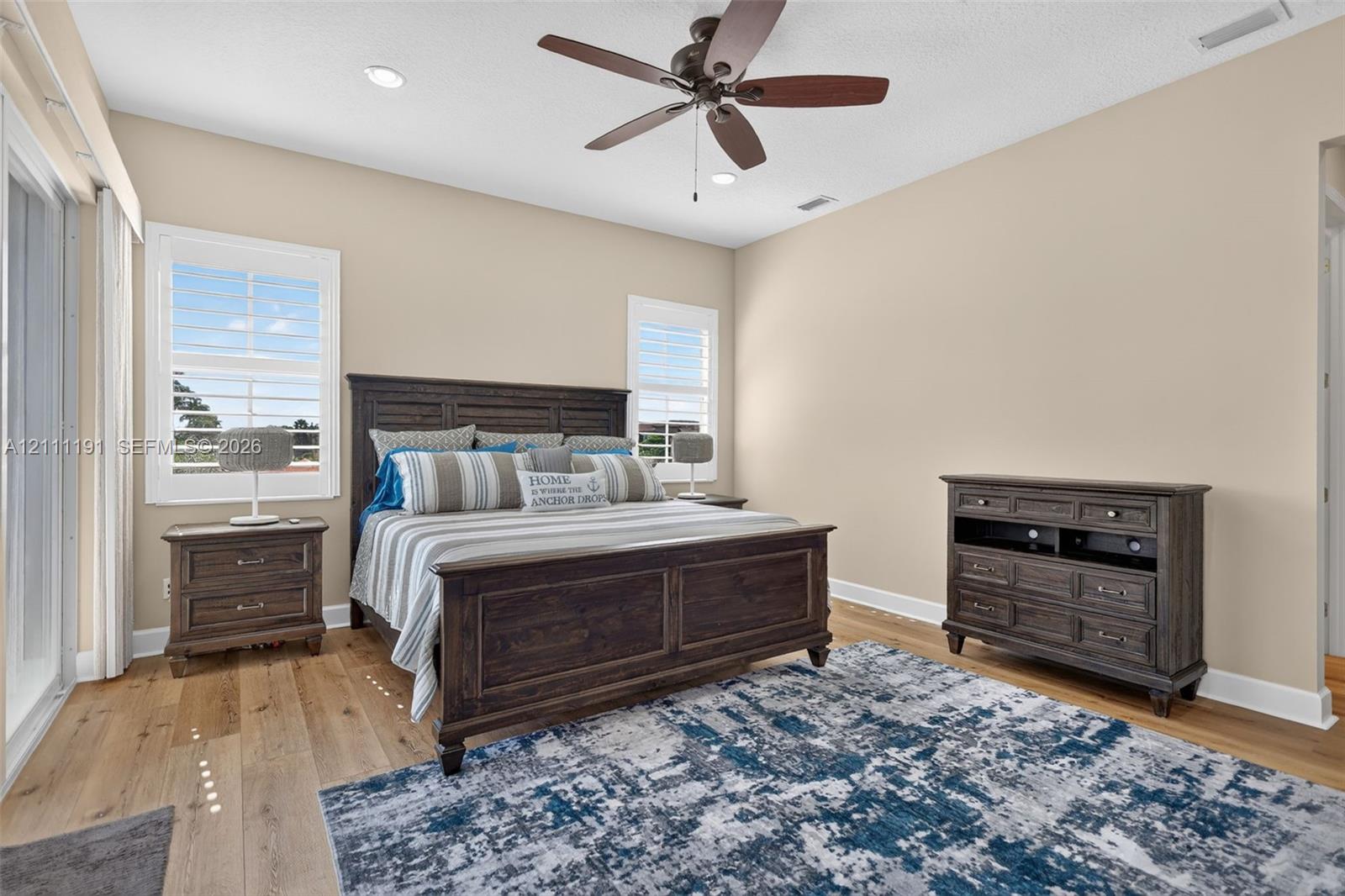 Neutral wall tones, wood-finish flooring, plantation shutters, and a central ceiling fan