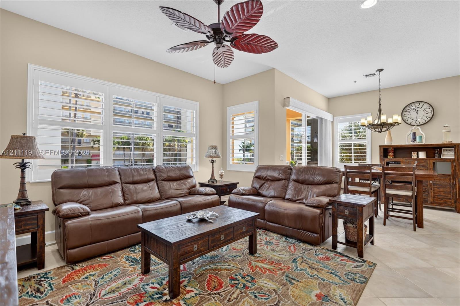 Open-concept interior featuring oversized tile flooring, plantation shutters, recessed lighting, and a decorative ceiling fan
