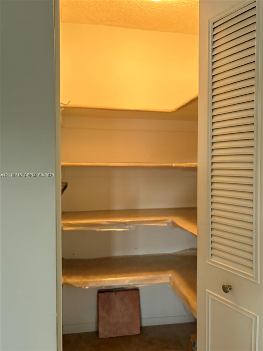 Storage space featuring tiered shelving and louvered door access