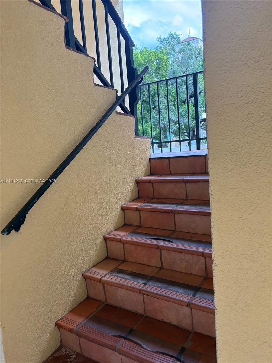 Stucco staircase featuring terracotta tile treads and black metal railings