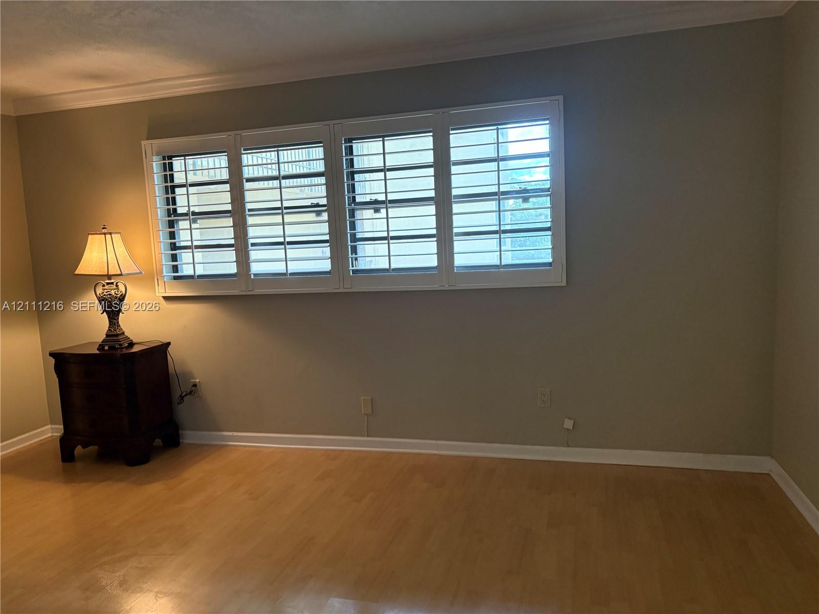 Expansive four-panel window featuring white plantation shutters and wood-finish flooring