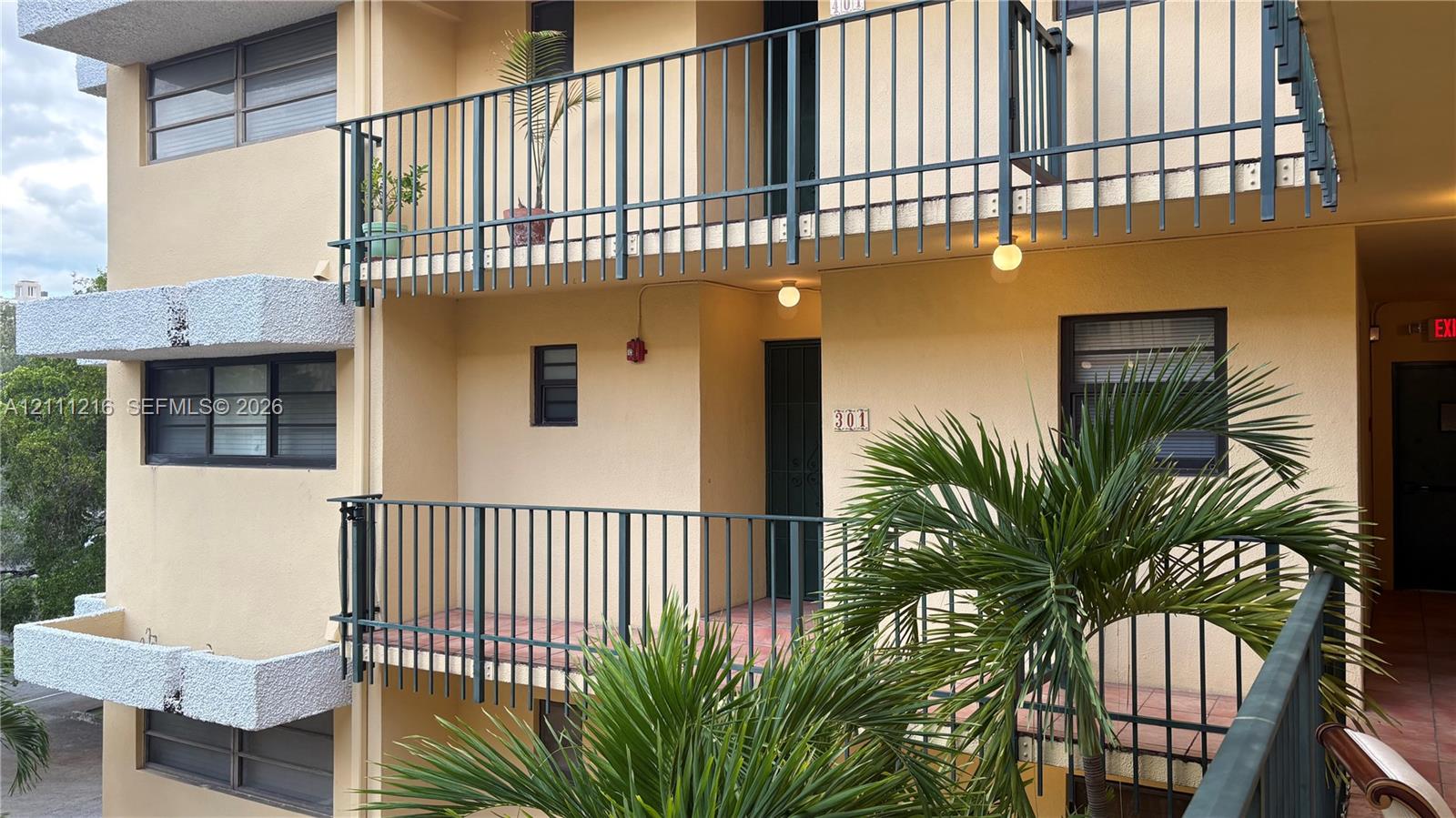 Multi-level exterior featuring stucco siding, metal railings, tiled balcony flooring, and horizontal sliding windows