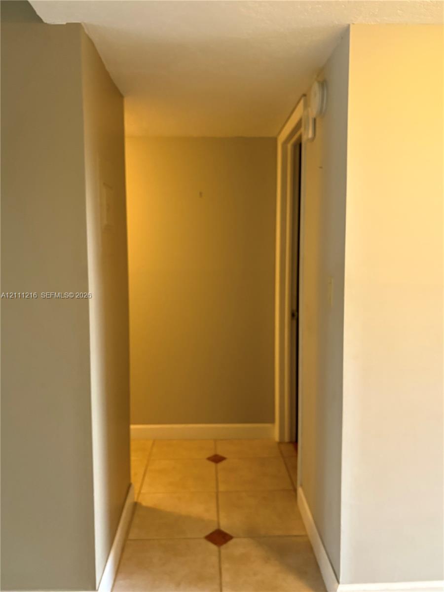 Hallway featuring neutral-toned walls and ceramic tile flooring with decorative inlay accents