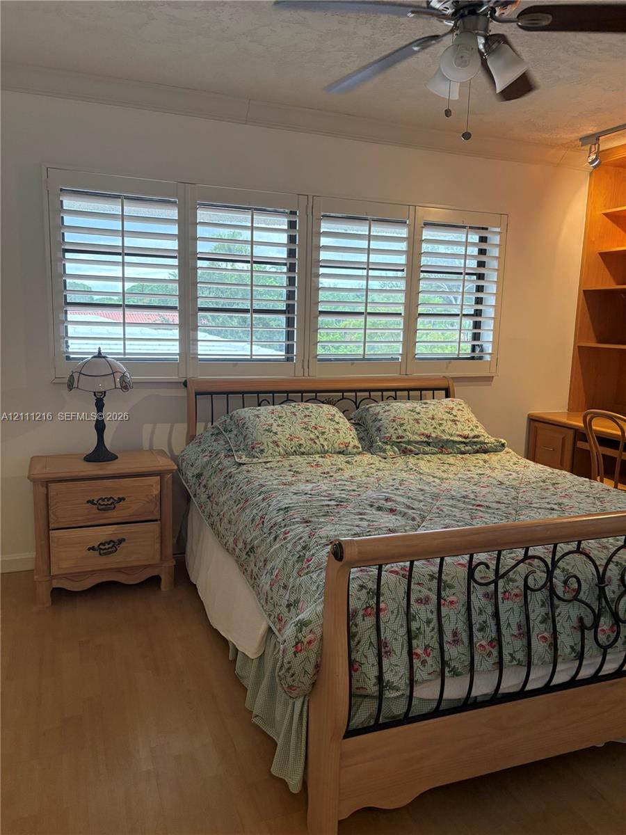 Wood-finish flooring, plantation shutters, and built-in floor-to-ceiling cabinetry with an integrated desk