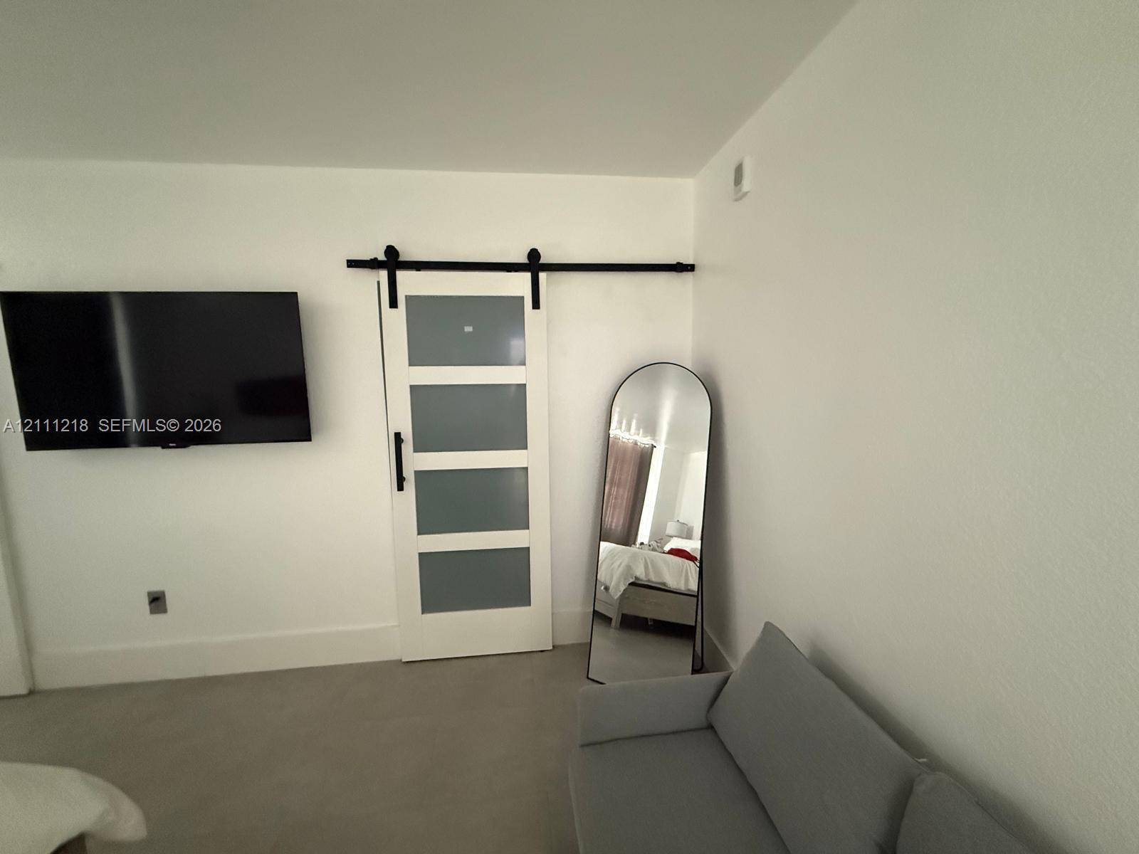 White interior door featuring frosted glass panels and a black metal sliding barn door track system