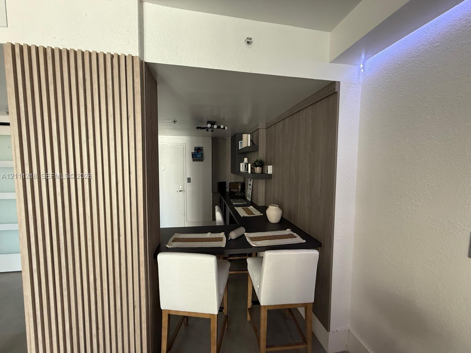 Vertical wood slat paneling, integrated wood-finish cabinetry, built-in recessed counter, and modern multi-bulb ceiling fixture Vertical wood slat paneling, integrated wood-finish cabinetry, built-in recessed counter, and modern multi-bulb ceiling fixture