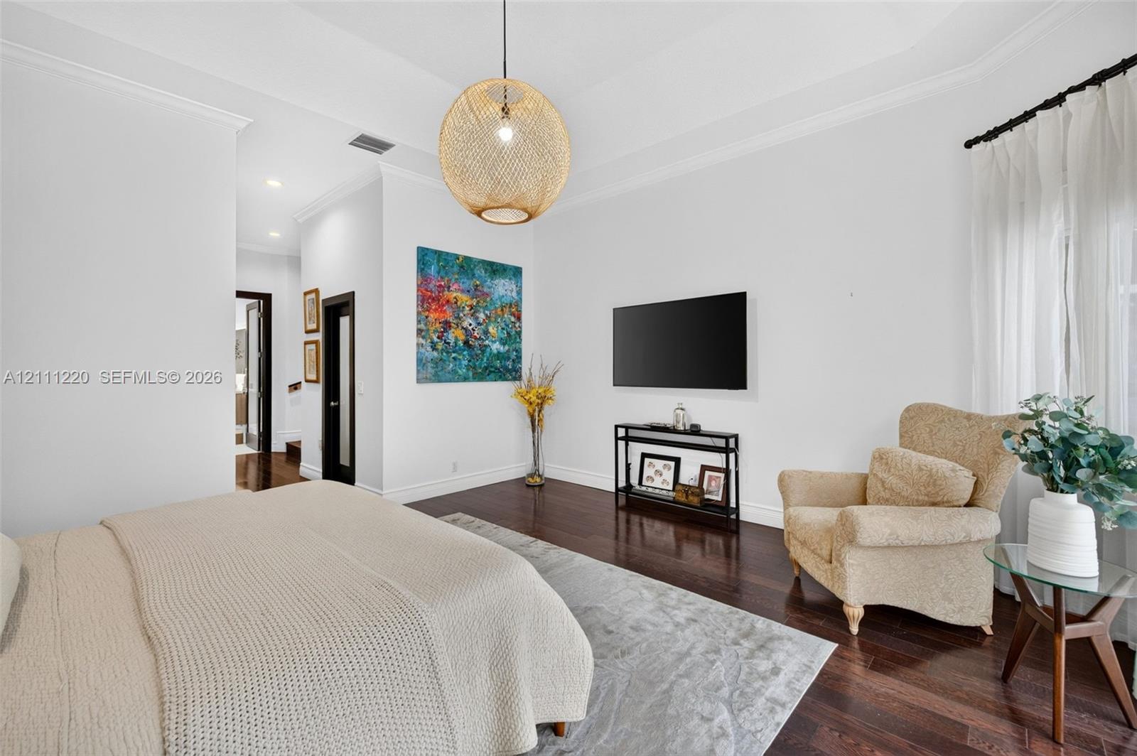 Tray ceiling, dark wood-finish flooring, crown molding, and woven spherical pendant lighting