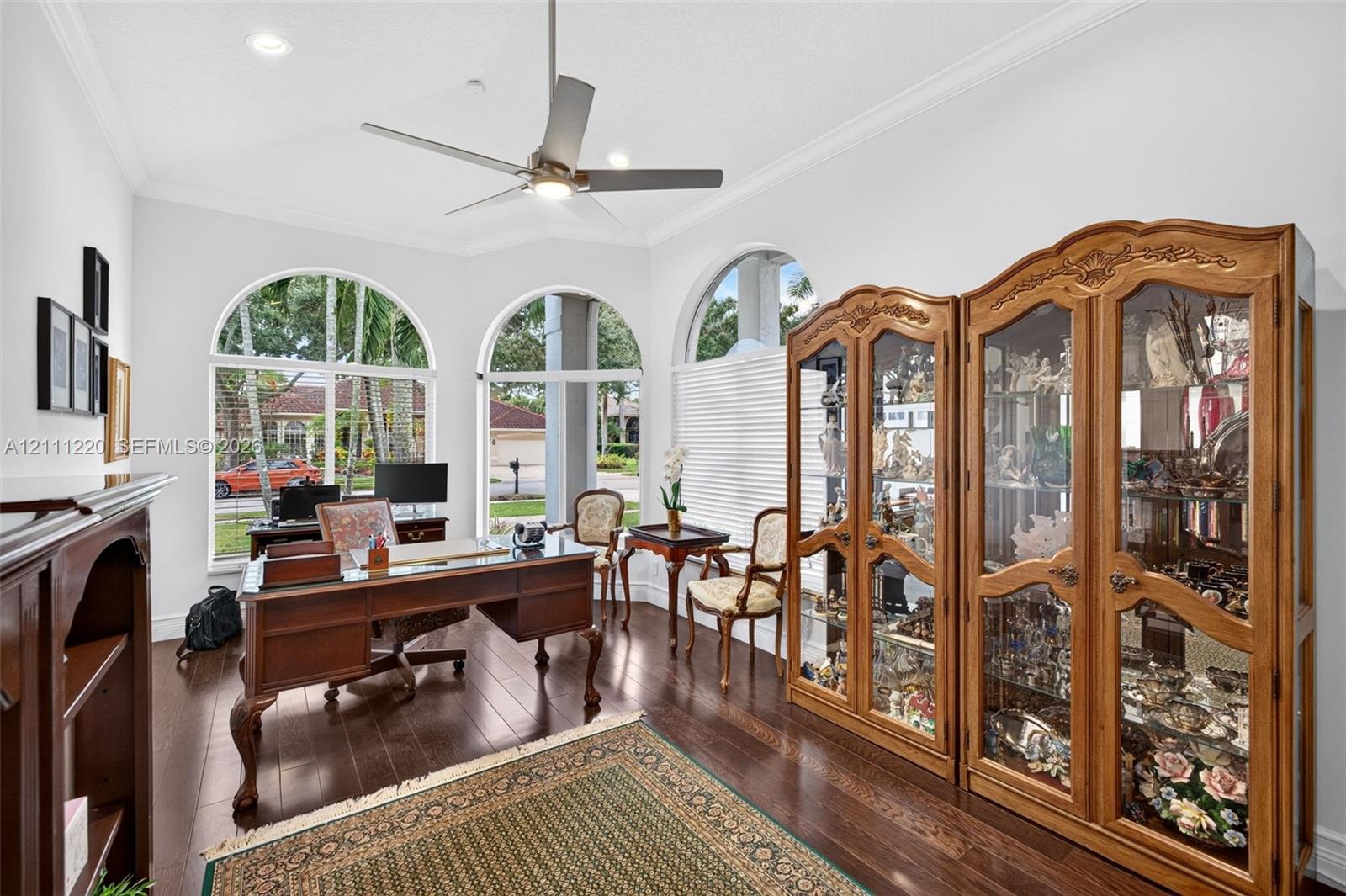 Wood-finish flooring, recessed lighting, ceiling fan, and arched windows with crown molding
