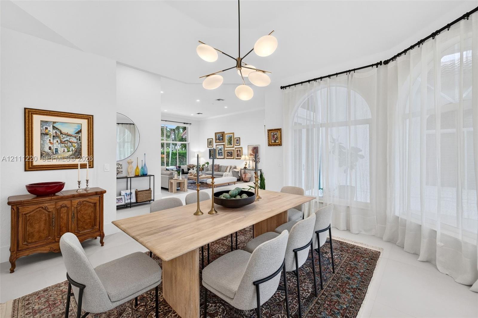 Dining space featuring arched windows, light-toned flooring, and a multi-arm modern chandelier