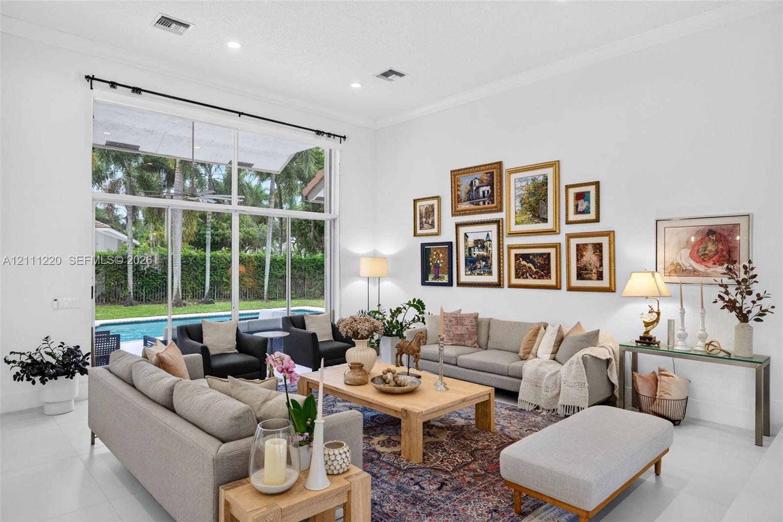 High-ceiling living area featuring floor-to-ceiling glass panel windows, recessed lighting, and large-format tile flooring