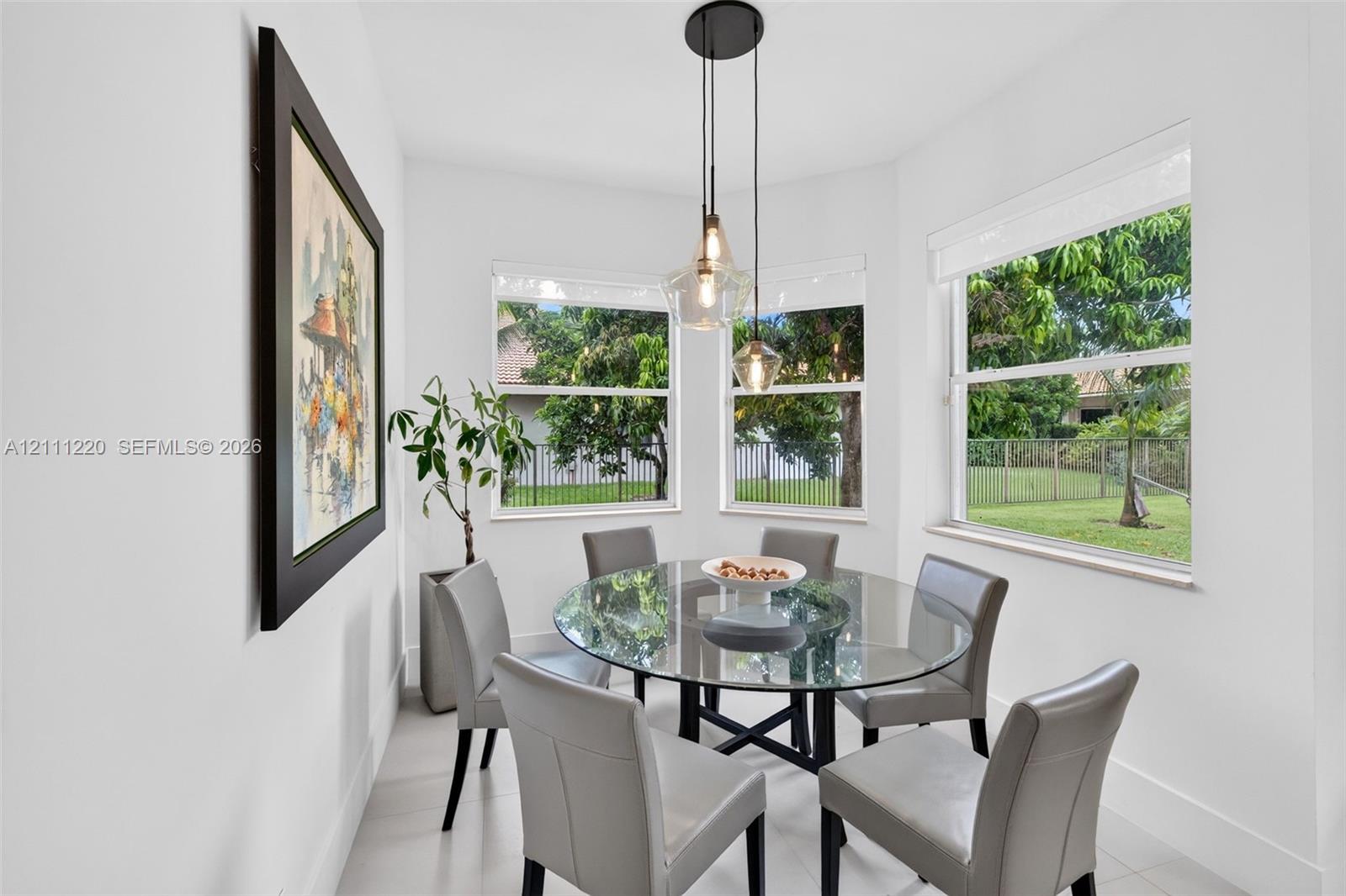 Sun-filled nook featuring triple-pane corner windows, pendant lighting with glass shades, and neutral floor tiling