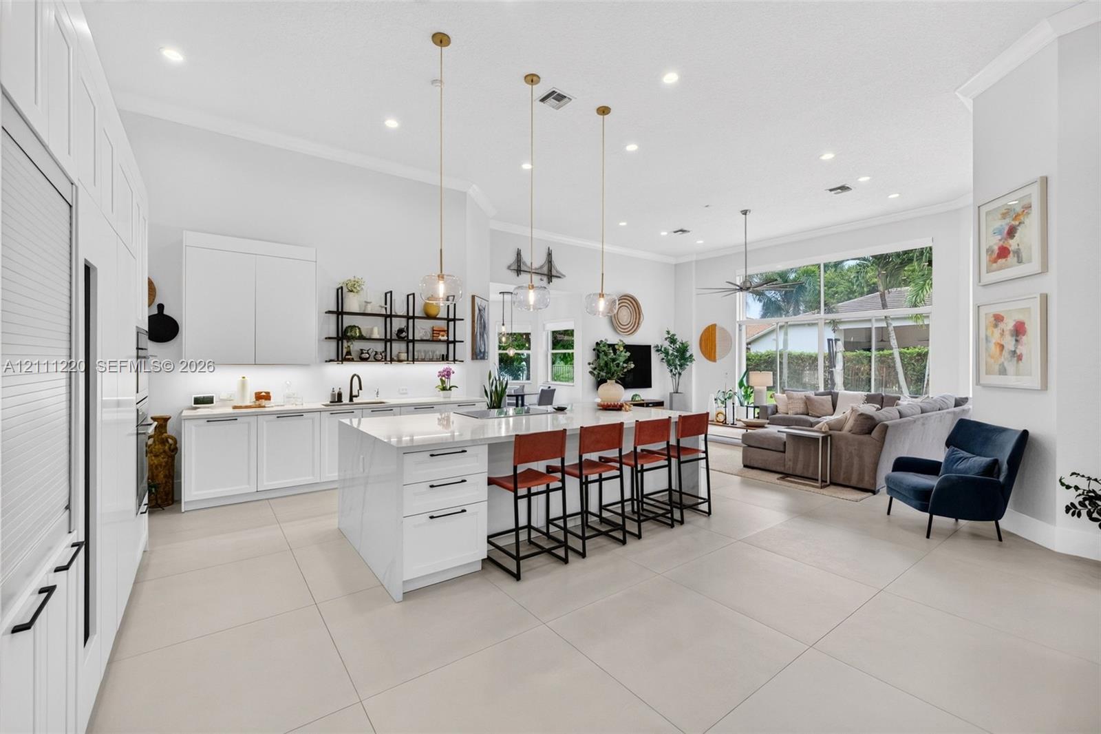 Kitchen featuring a large central island with quartz surfacing, floor-to-ceiling white cabinetry, matte black hardware, recessed lighting, and large-format tile flooring