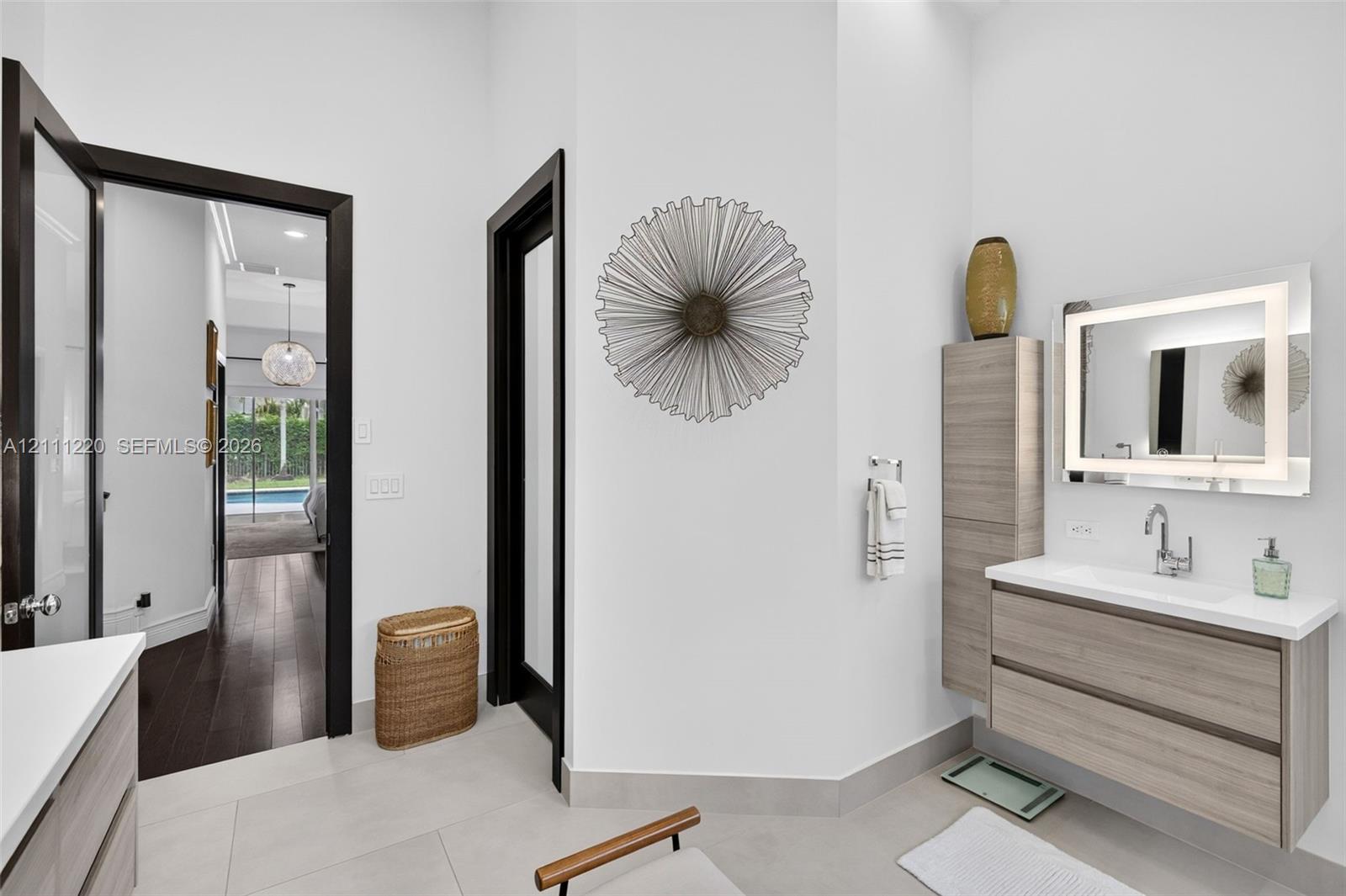 Floating vanity with wood-finish cabinetry, integrated countertop, and LED-backlit mirror
