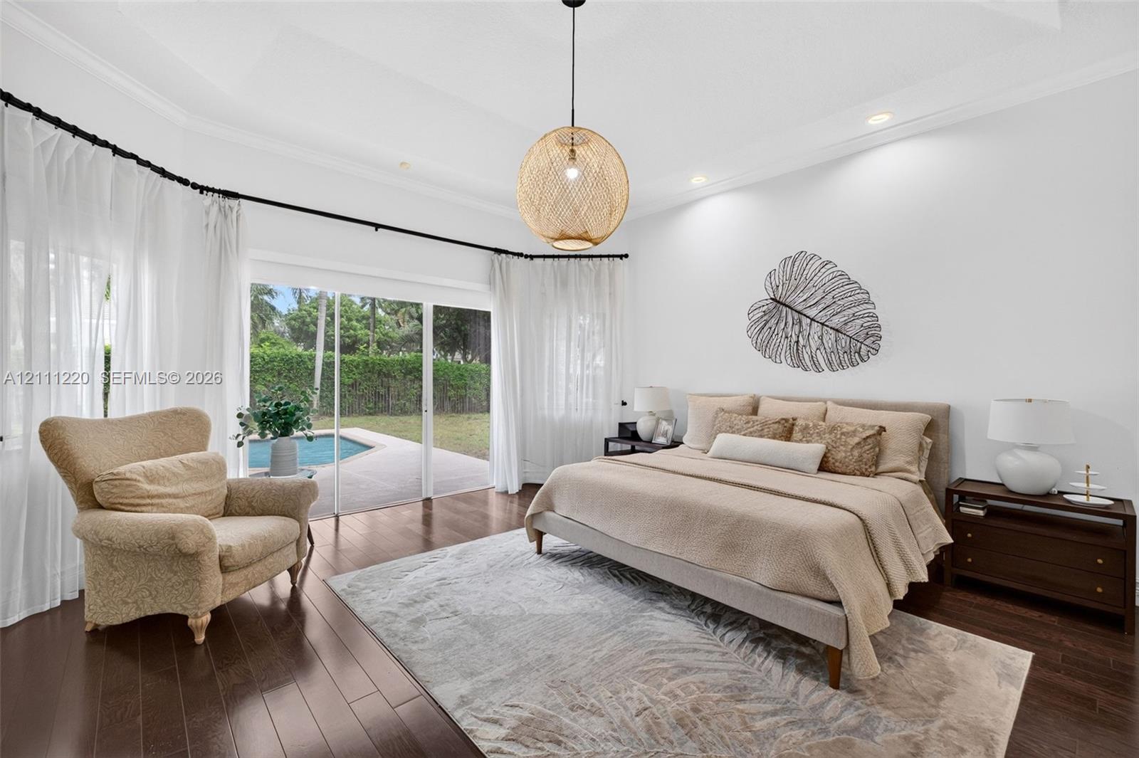 Tray ceiling with recessed lighting, dark wood-finish flooring, and sliding glass doors opening to an exterior swimming pool