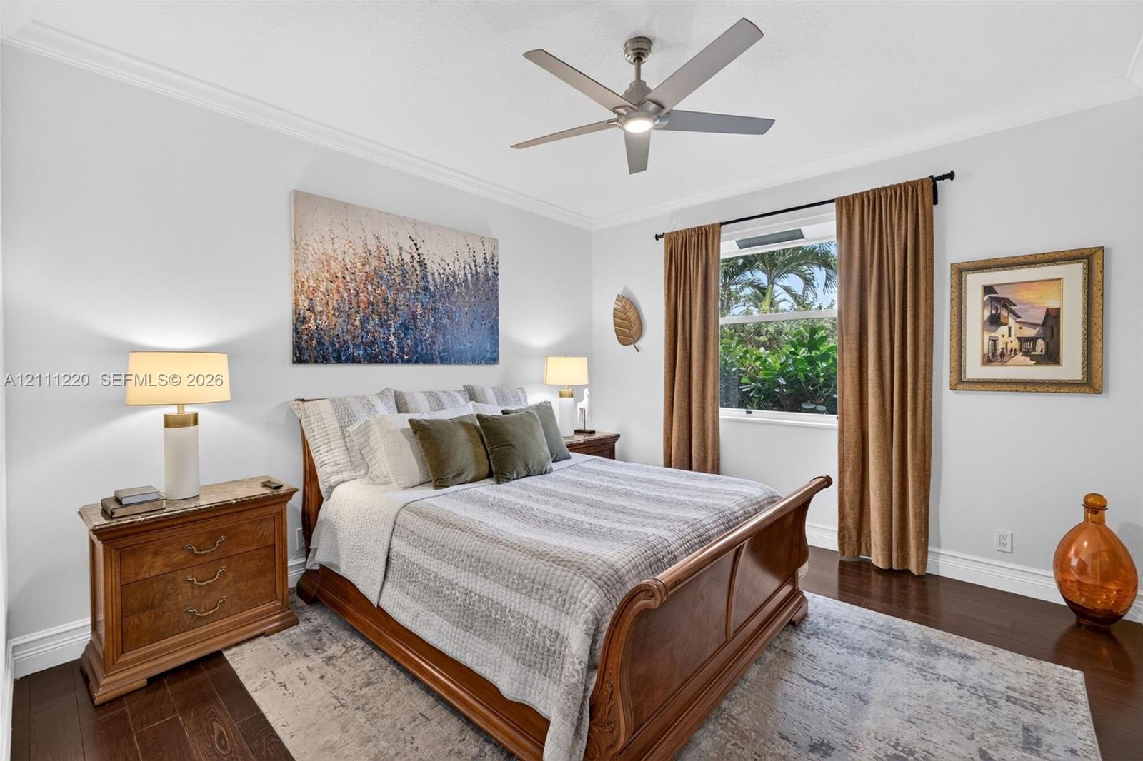 Dark-toned wood-finish flooring, ceiling fan with integrated lighting, and crown molding