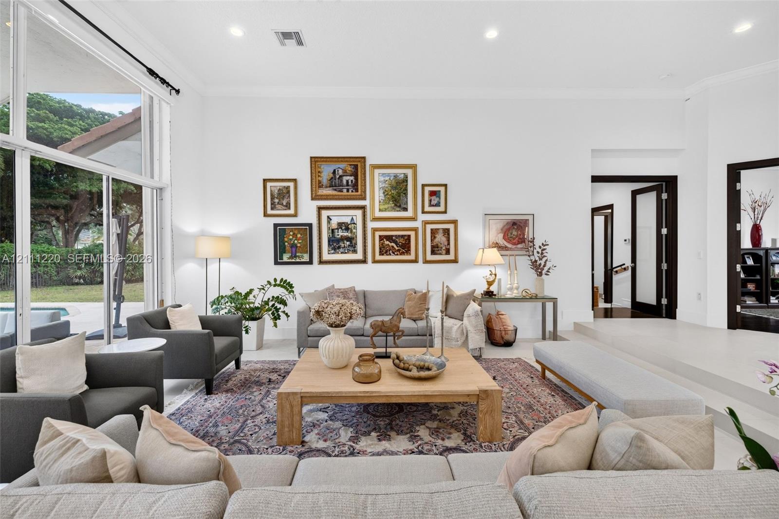Living area featuring high ceilings, large-format tile flooring, recessed lighting, and expansive floor-to-ceiling windows
