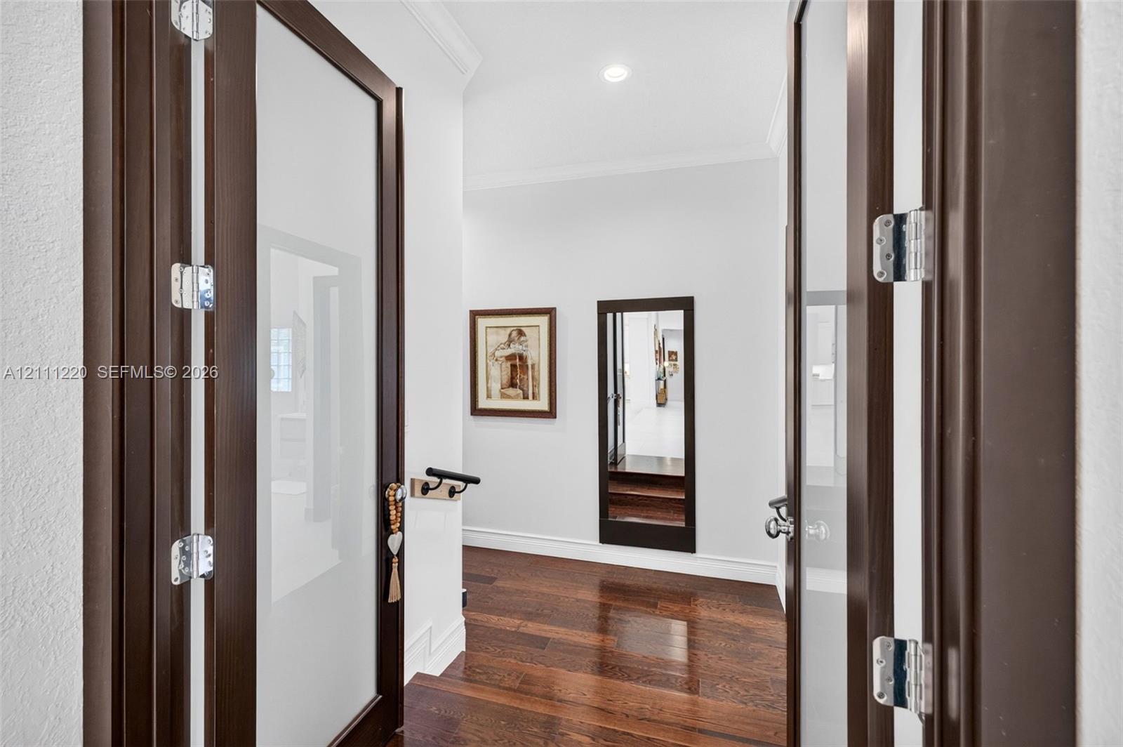 Double doors featuring dark wood frames with frosted glass panels, wood-finish flooring, and recessed ceiling lighting
