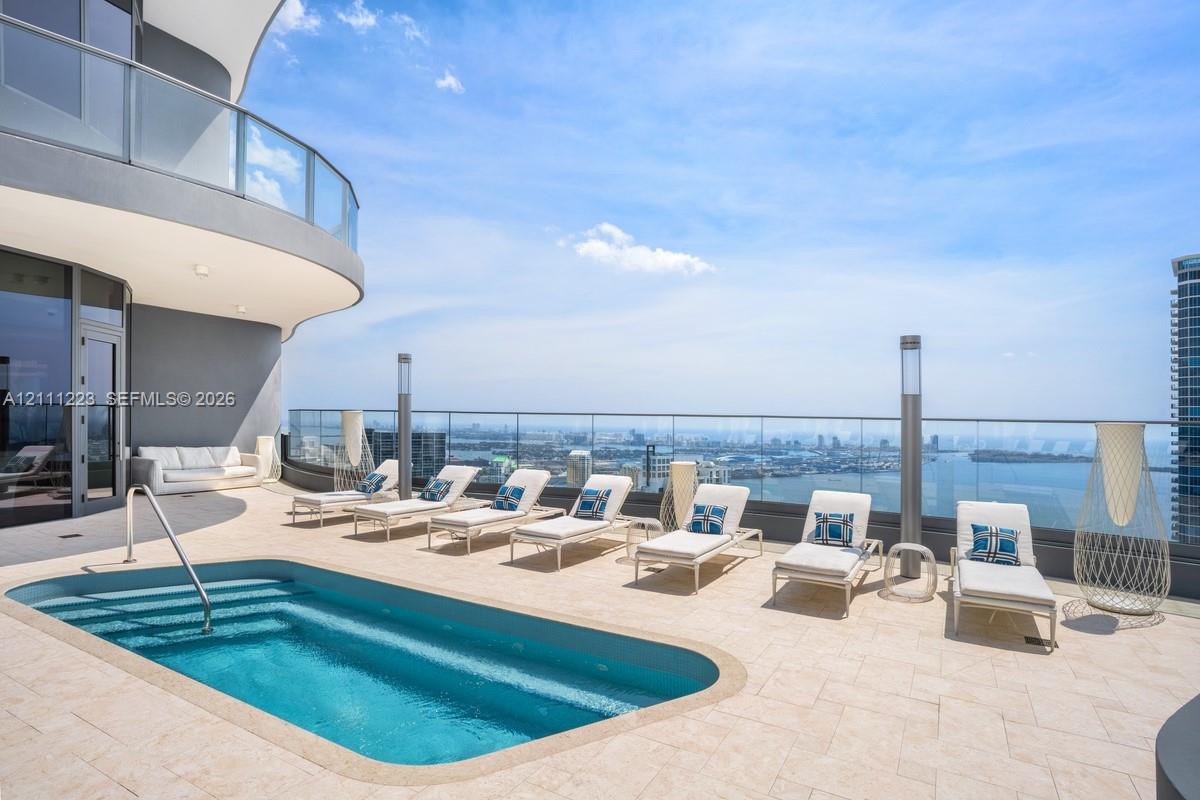 Expansive terrace featuring stone-tiled flooring, a built-in plunge pool with stainless steel handrail, and a frameless glass perimeter railing