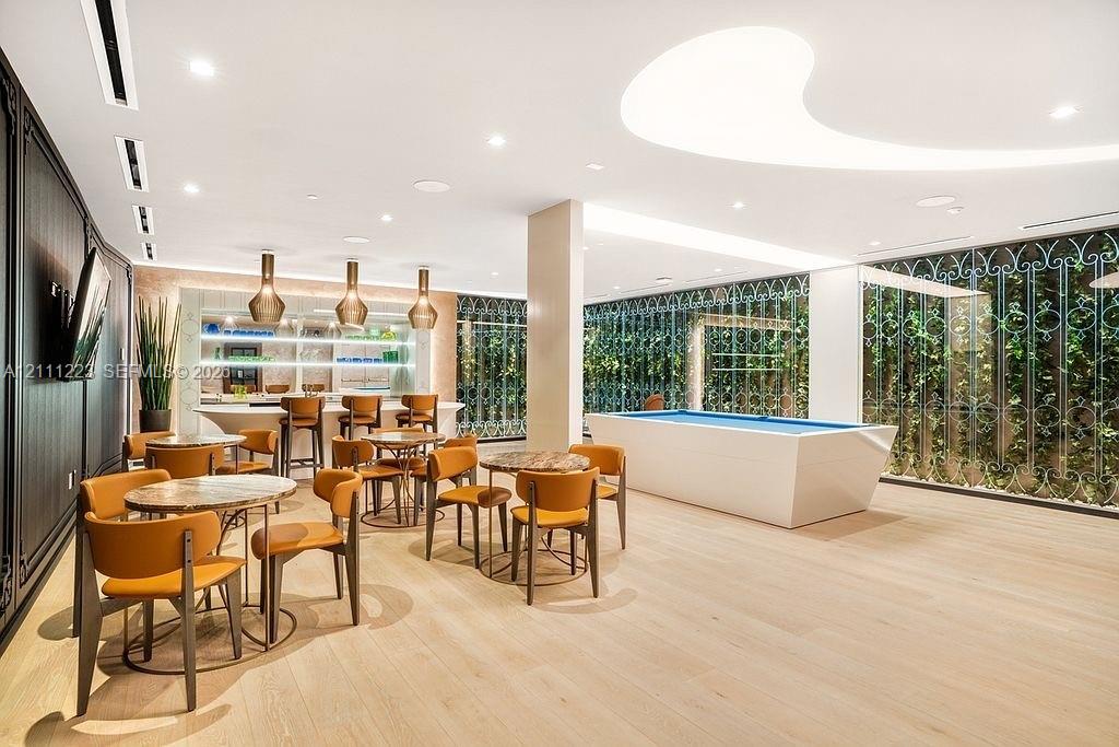 Interior space featuring wood-finish flooring, custom ceiling lighting with a curved recessed design, built-in wet bar with integrated shelving, and floor-to-ceiling decorative metal screens