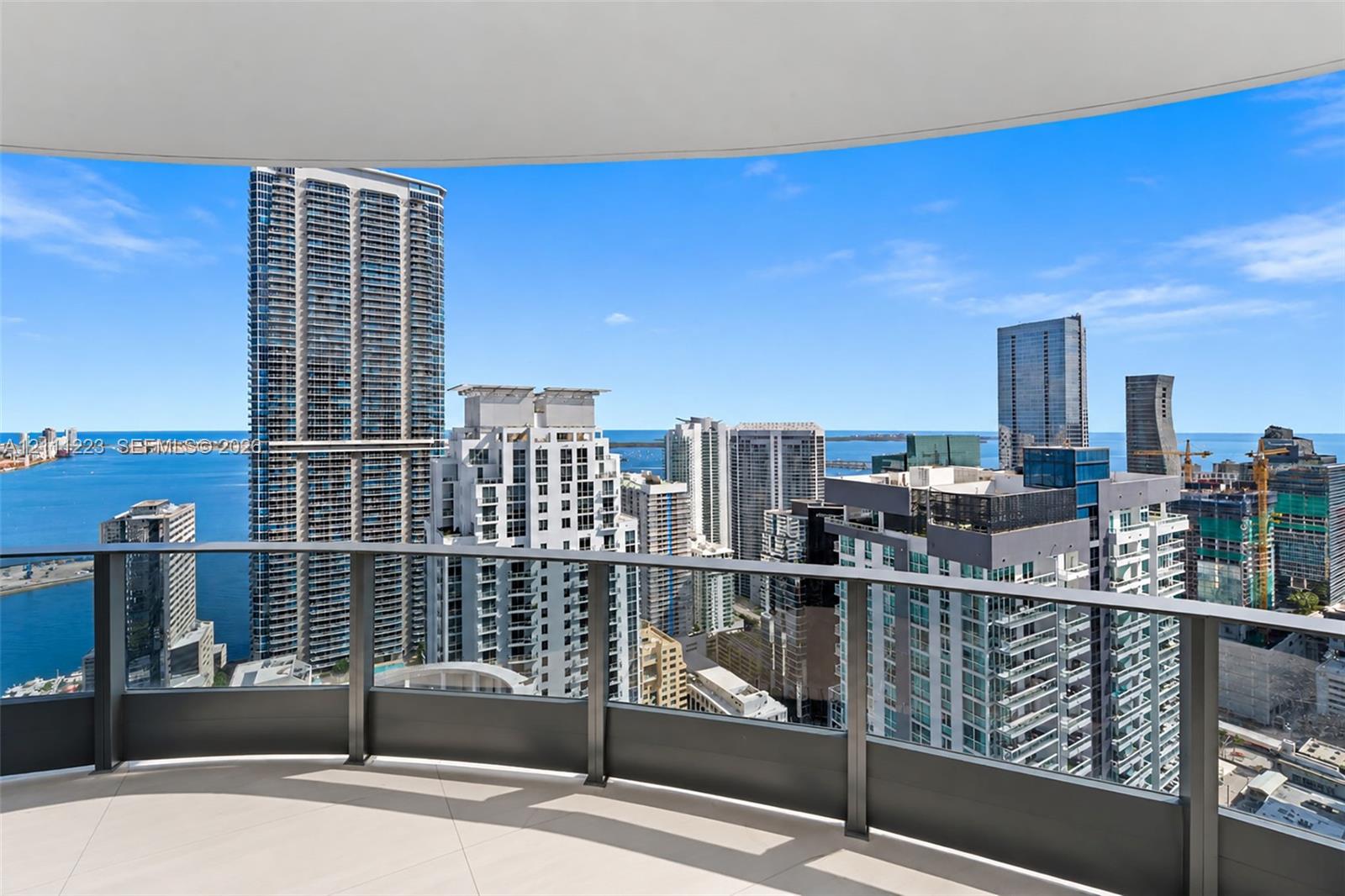 Curved covered balcony featuring large-format tile flooring and dark metal railing