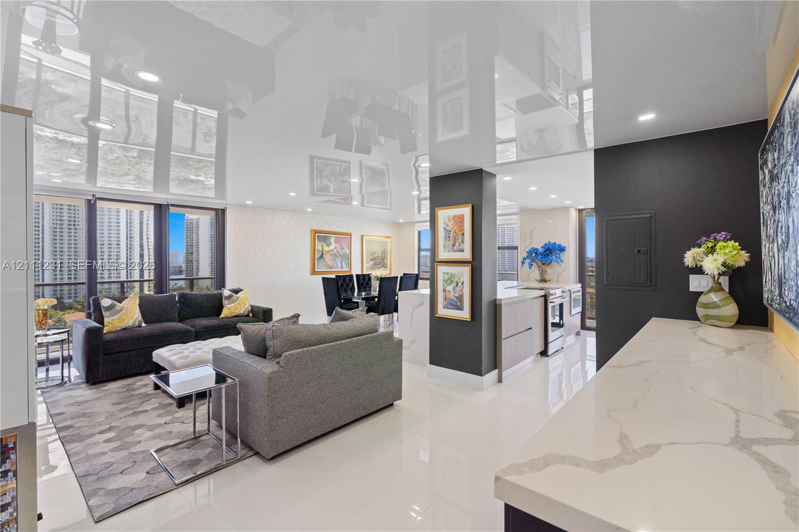 High-gloss reflective ceiling, stone countertop with waterfall edge, recessed lighting, floor-to-ceiling windows, and polished porcelain flooring
