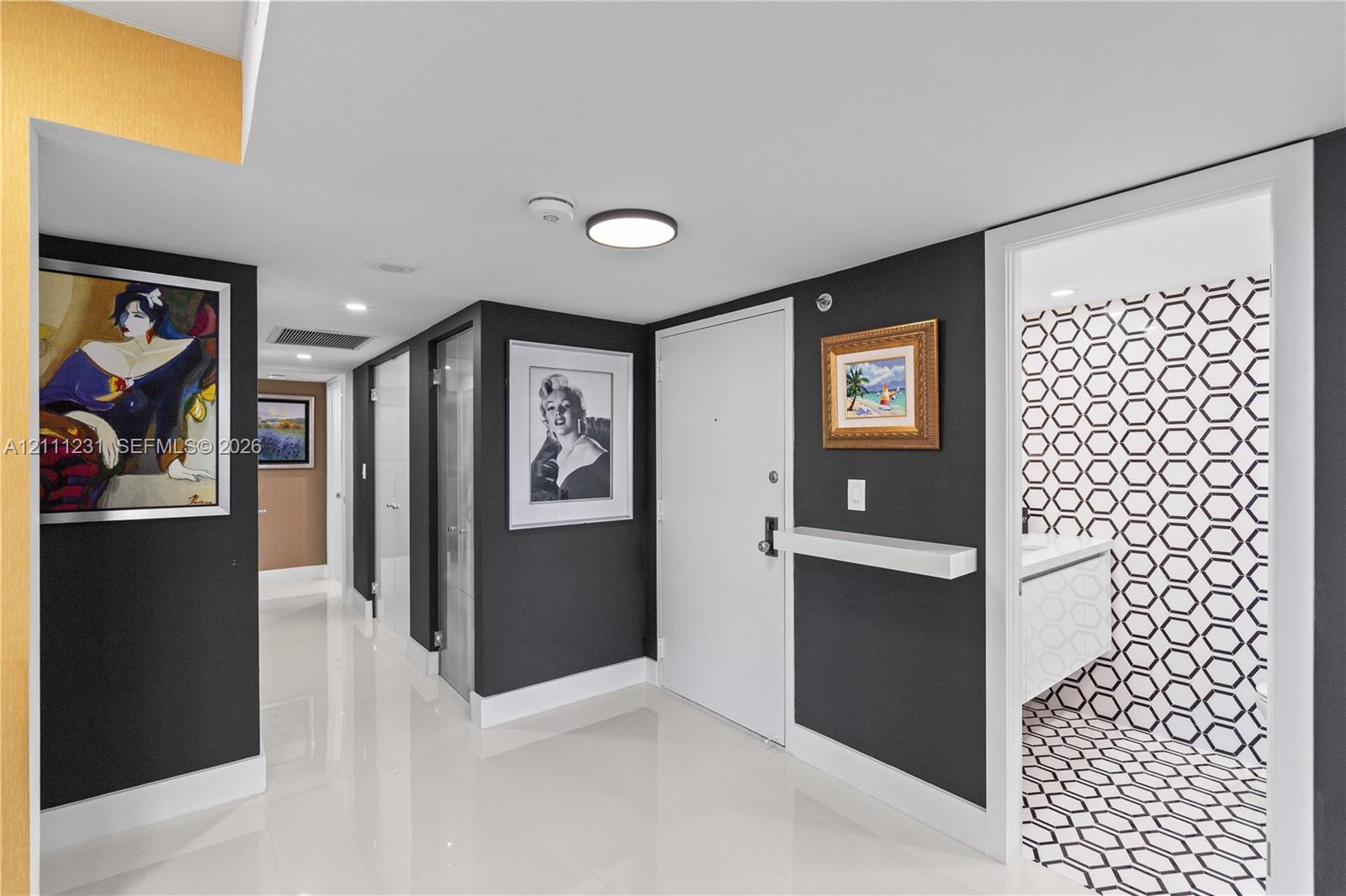 Entryway featuring polished large-format tile flooring, high-contrast dark wall finishes, and a built-in wall-mounted shelf
