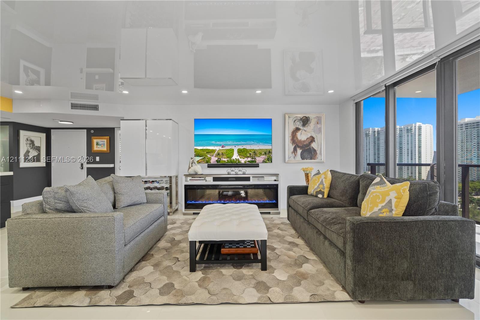 High-gloss reflective ceiling, built-in electric fireplace, floor-to-ceiling glass windows, and light-toned tile flooring