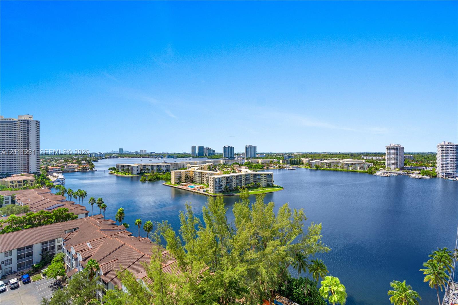 Panoramic waterfront perspective featuring expansive lake scenery, tropical landscaping, and mid-rise residential architecture