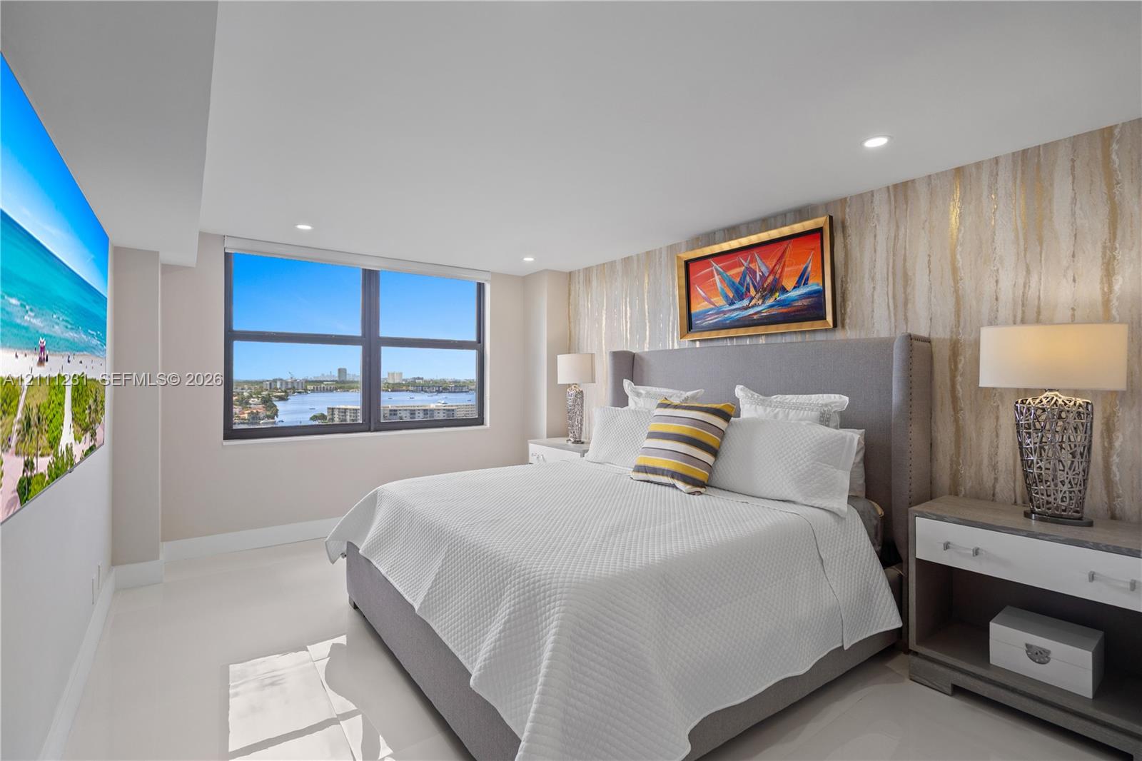 Large windows with water and skyline scenery, polished stone-finish flooring, recessed lighting, and a decorative textured accent wall