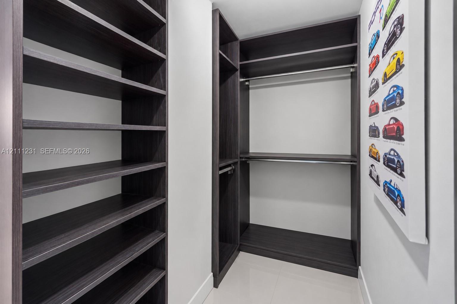 Custom walk-in closet featuring dark wood-finish shelving, integrated hanging rods, and multiple open storage compartments