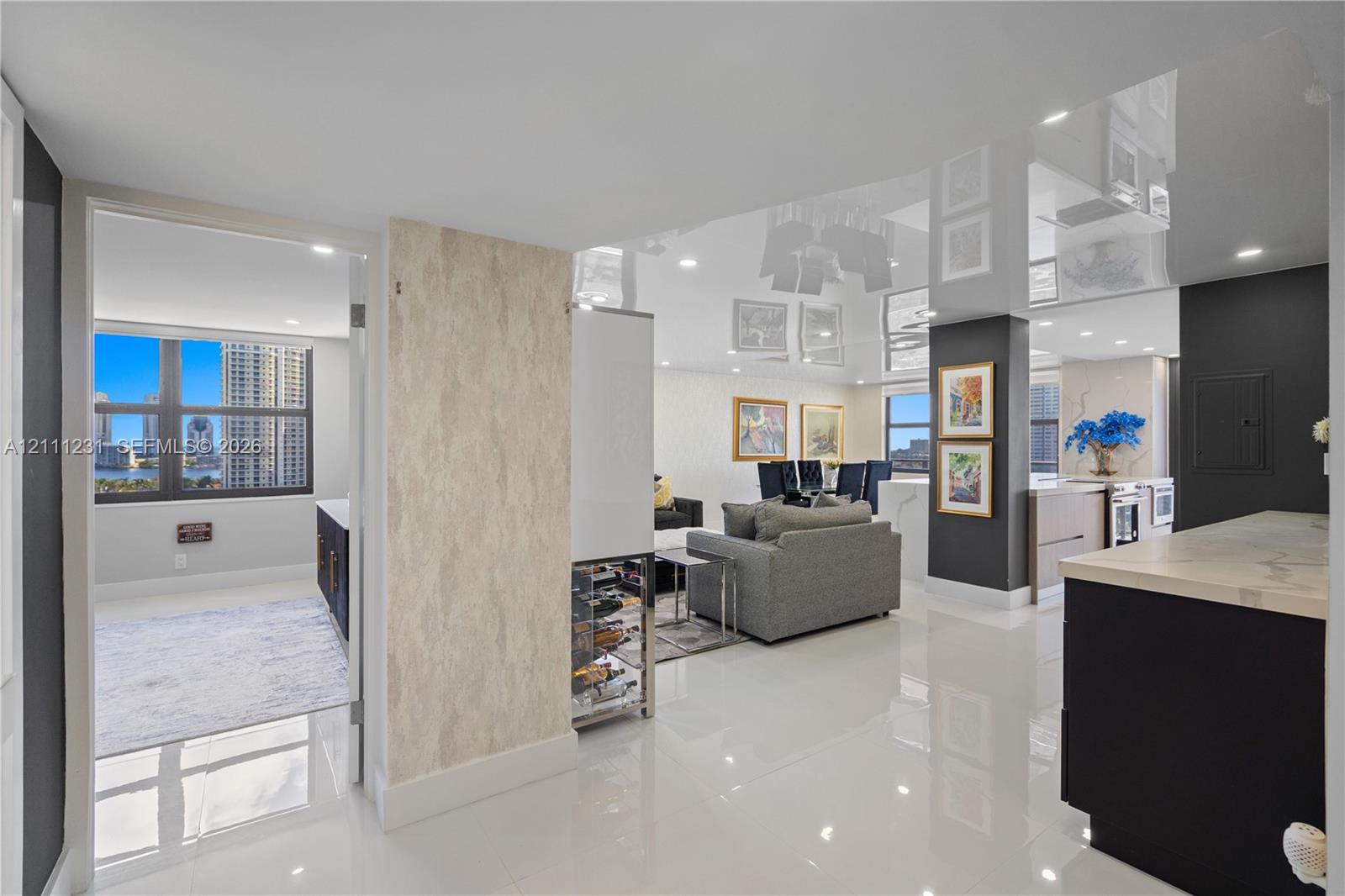Polished high-gloss ceiling, large-format tile flooring, built-in wine refrigeration, stone-finish feature wall, and dark cabinetry with stone countertops
