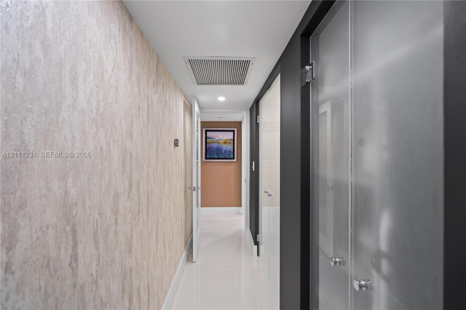 Hallway featuring textured wallpaper, high-gloss tile flooring, and frosted glass panel doors