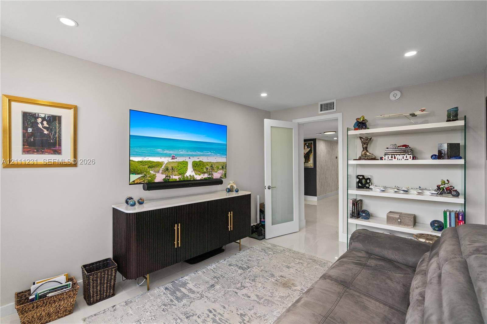 Interior space featuring recessed lighting, smooth surface flooring, a built-in glass-shelf display unit, and a door with a frosted glass panel