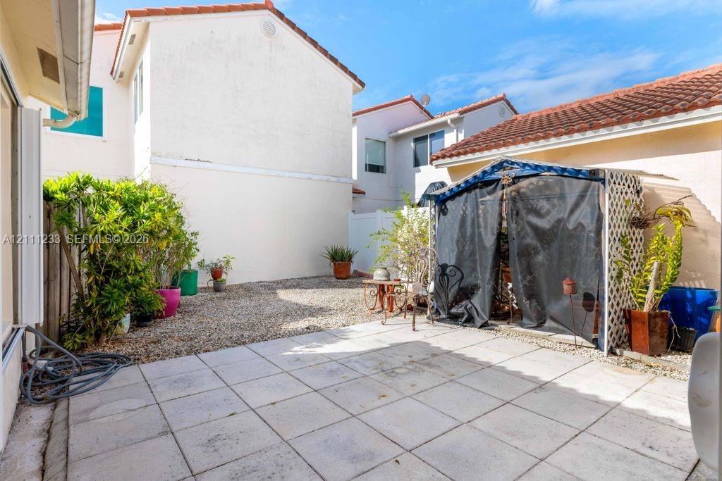 Private courtyard featuring square paver patio, stone-surfaced ground, and stucco exterior walls