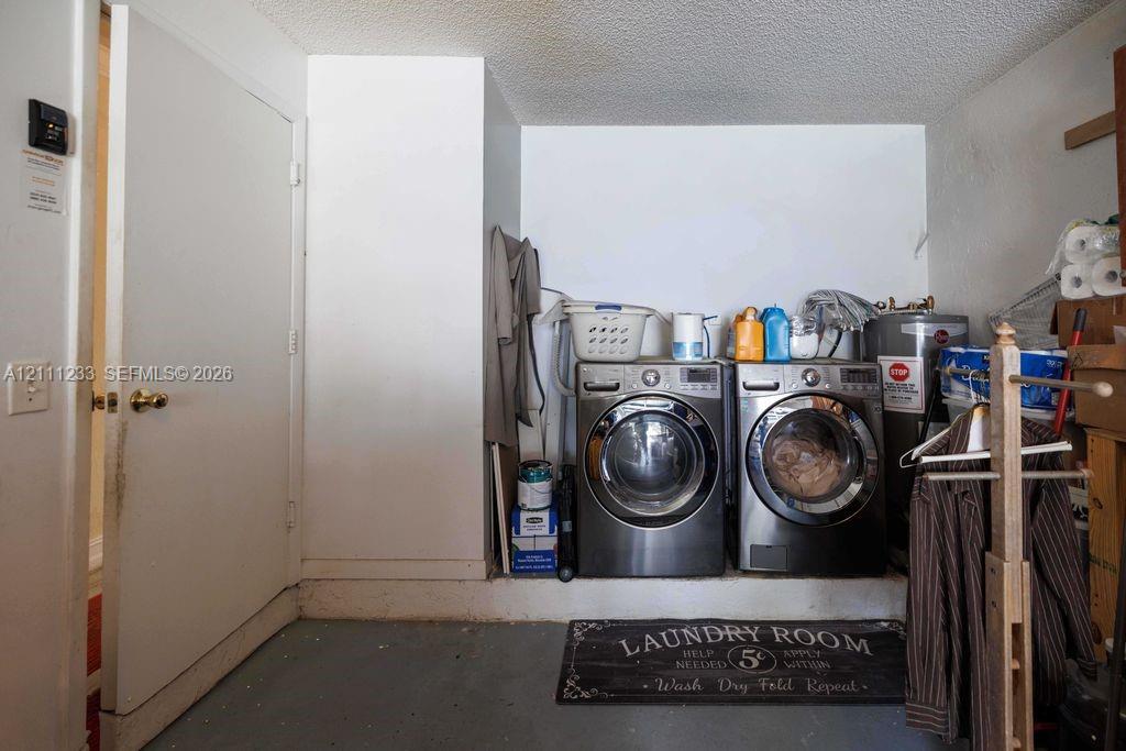 Dedicated laundry space featuring stainless steel front-load appliances and a concrete flooring surface