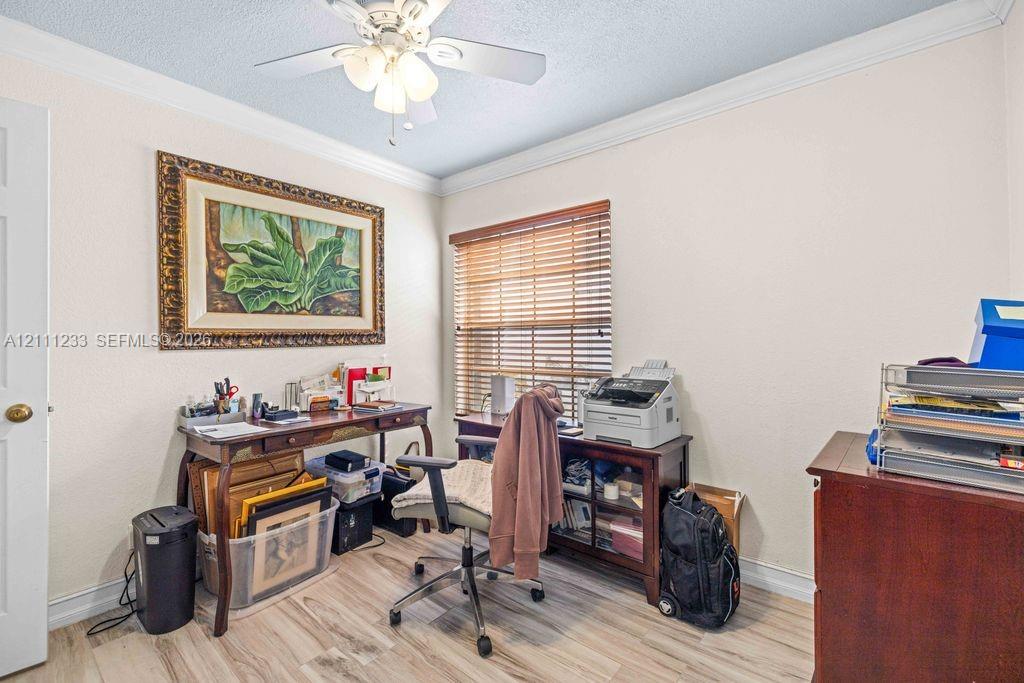 Room featuring crown molding, wood-finish flooring, and a ceiling fan with integrated lighting