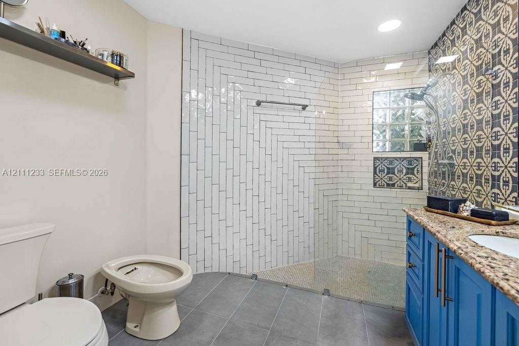 Walk-in shower featuring a herringbone tile surround, glass partition, and a glass block accent window