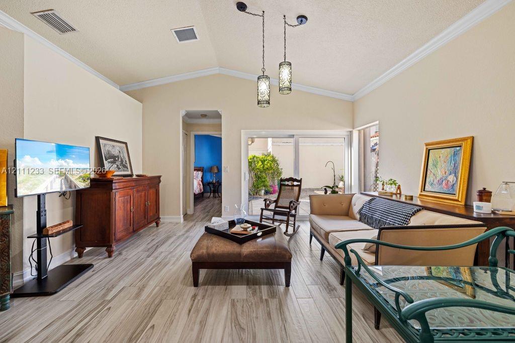 Vaulted ceilings featuring decorative pendant lighting, sliding glass doors, and wood-finish flooring Vaulted ceilings featuring decorative pendant lighting, sliding glass doors, and wood-finish flooring