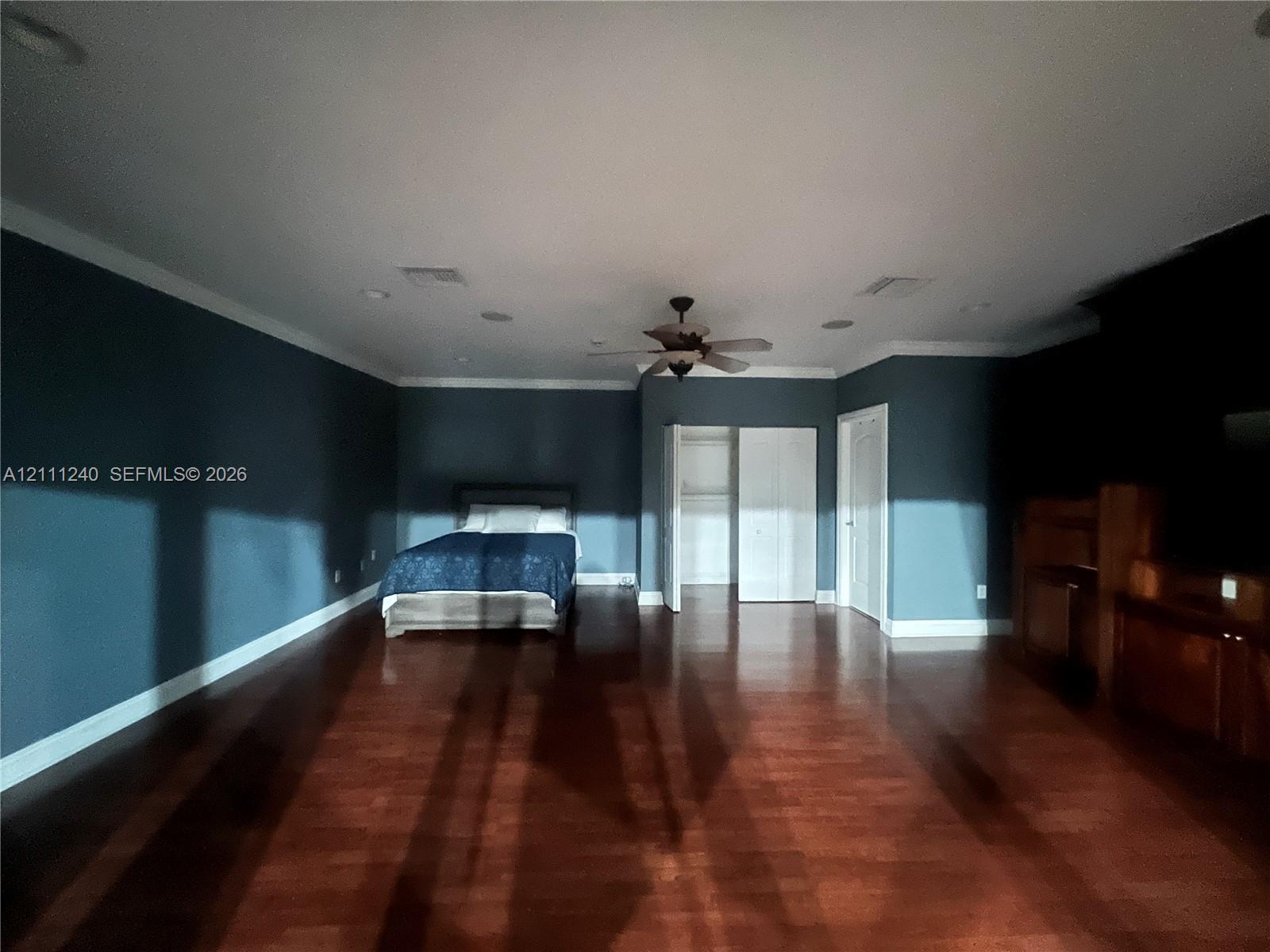 Spacious room featuring wood-finish flooring, crown molding, recessed lighting, and a ceiling fan